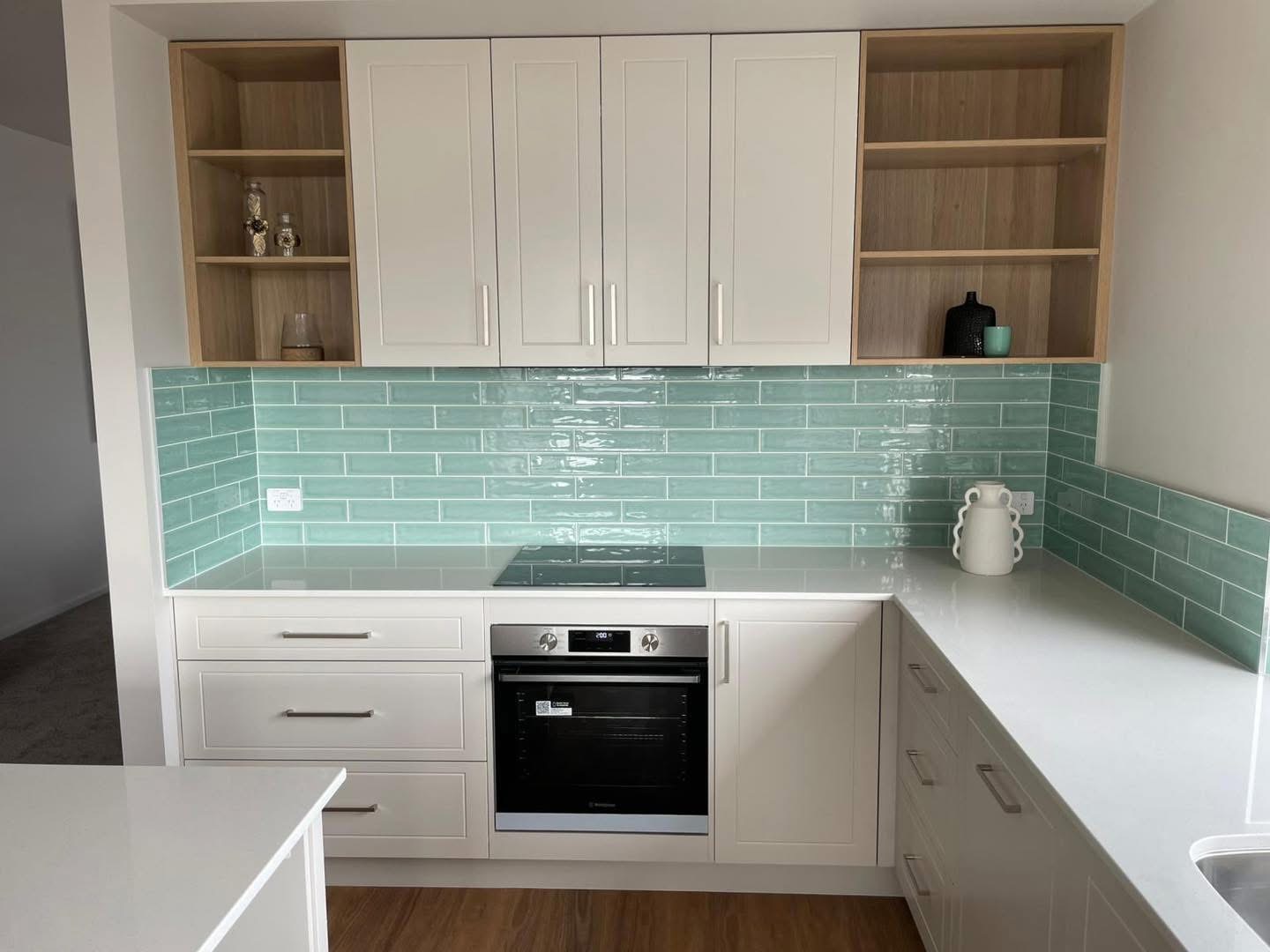 White shaker kitchen with oak open shelving and a mint green splashback, built by Central Coast Joinery