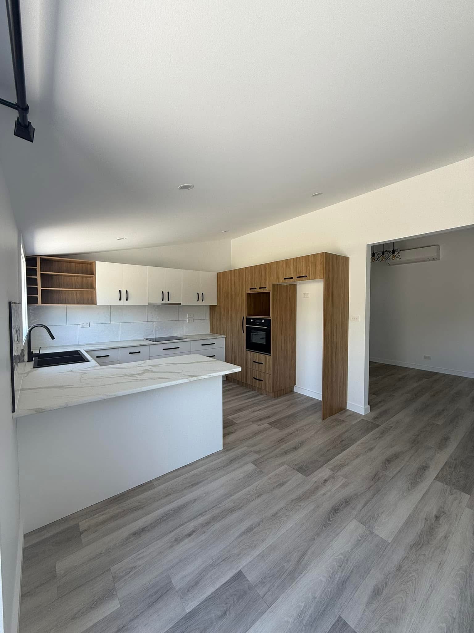 White kitchen with woodgrain tall cabinetry and a marble-look benchtop, built by Central Coast Joinery